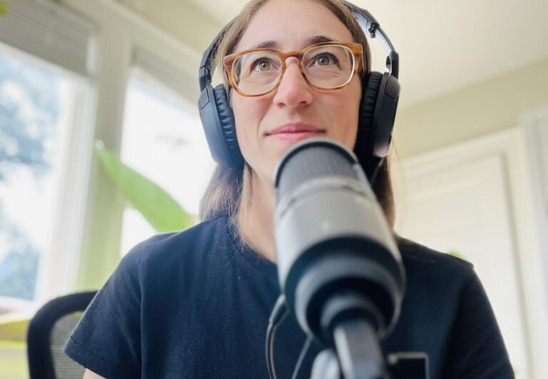 me, wearing headphones behind a microphone recording a podcast